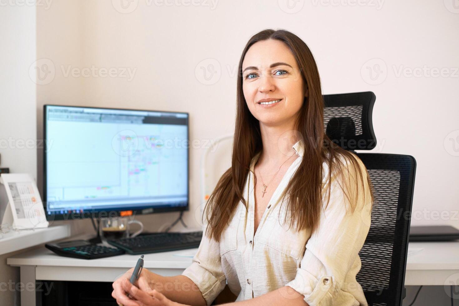 Portrait of a remote worker. A beautiful woman sits at a table in front of a computer and designs a building. Confident young lady freelancer working from home. photo