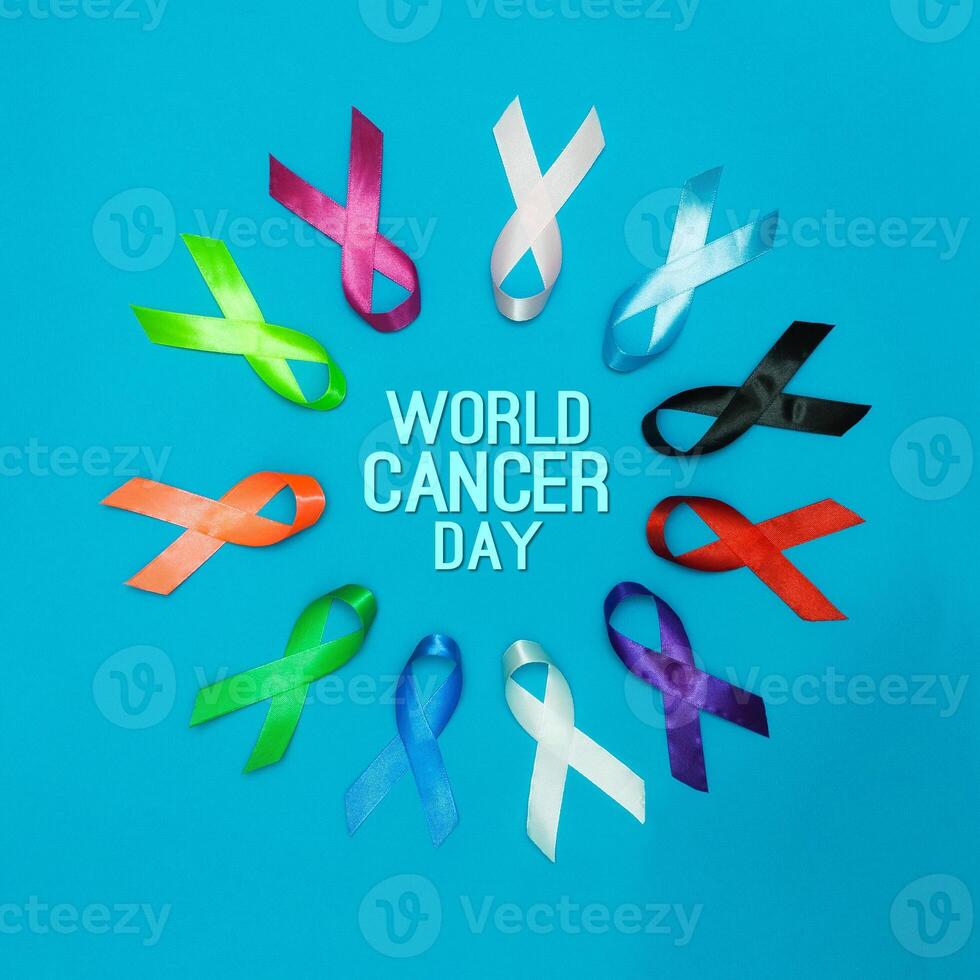 Paper with text WORLD CANCER DAY February 4 background. Colorful ribbons, cancer awareness. blue surface from above photo