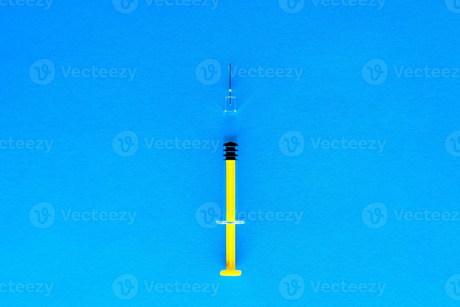 Yellow glass medical syringe over dark background photo