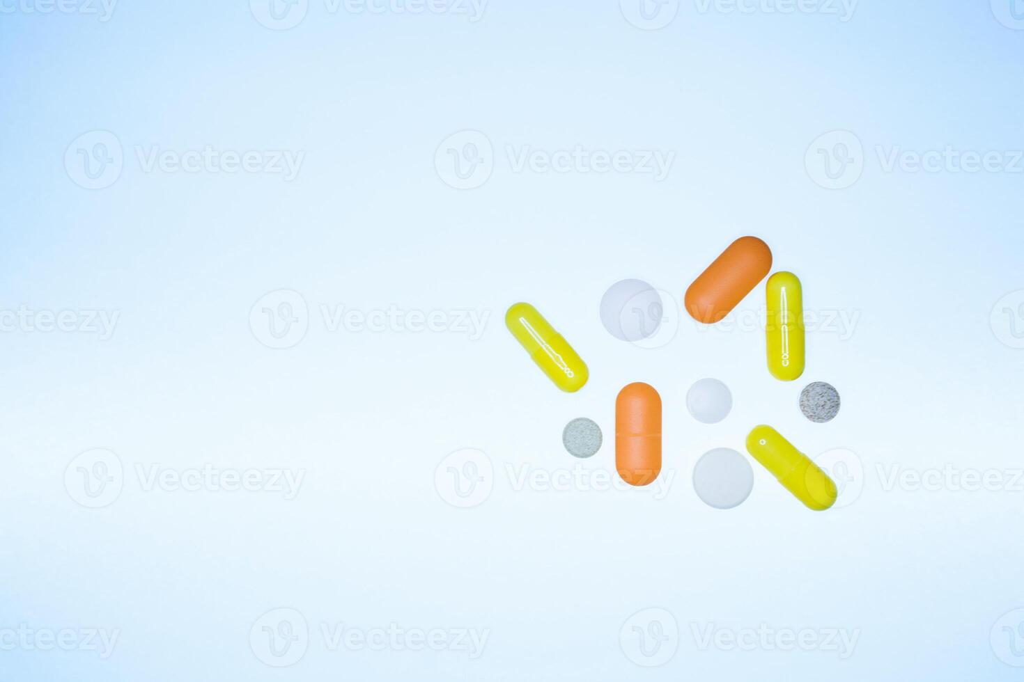 colored pills, capsules, vitamins flying out of a vial on a blue background, life concept, closeup, copy space photo