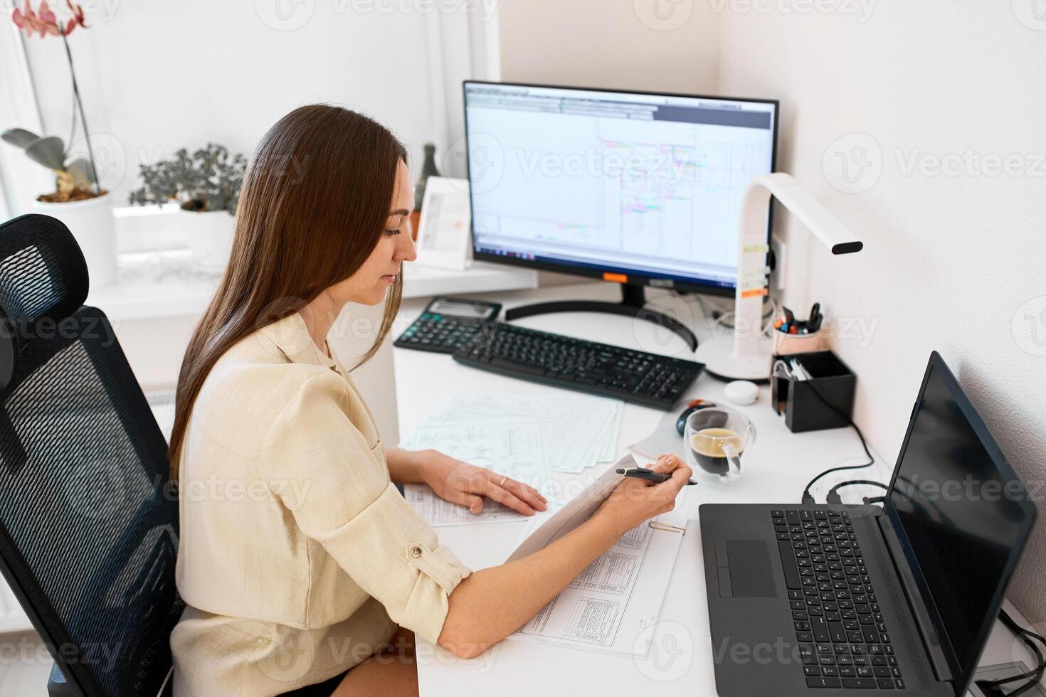 Portrait of a remote worker. An adult woman sits at a table in front of a computer and draws up a costly estimate. Confident young lady freelancer working from home. photo