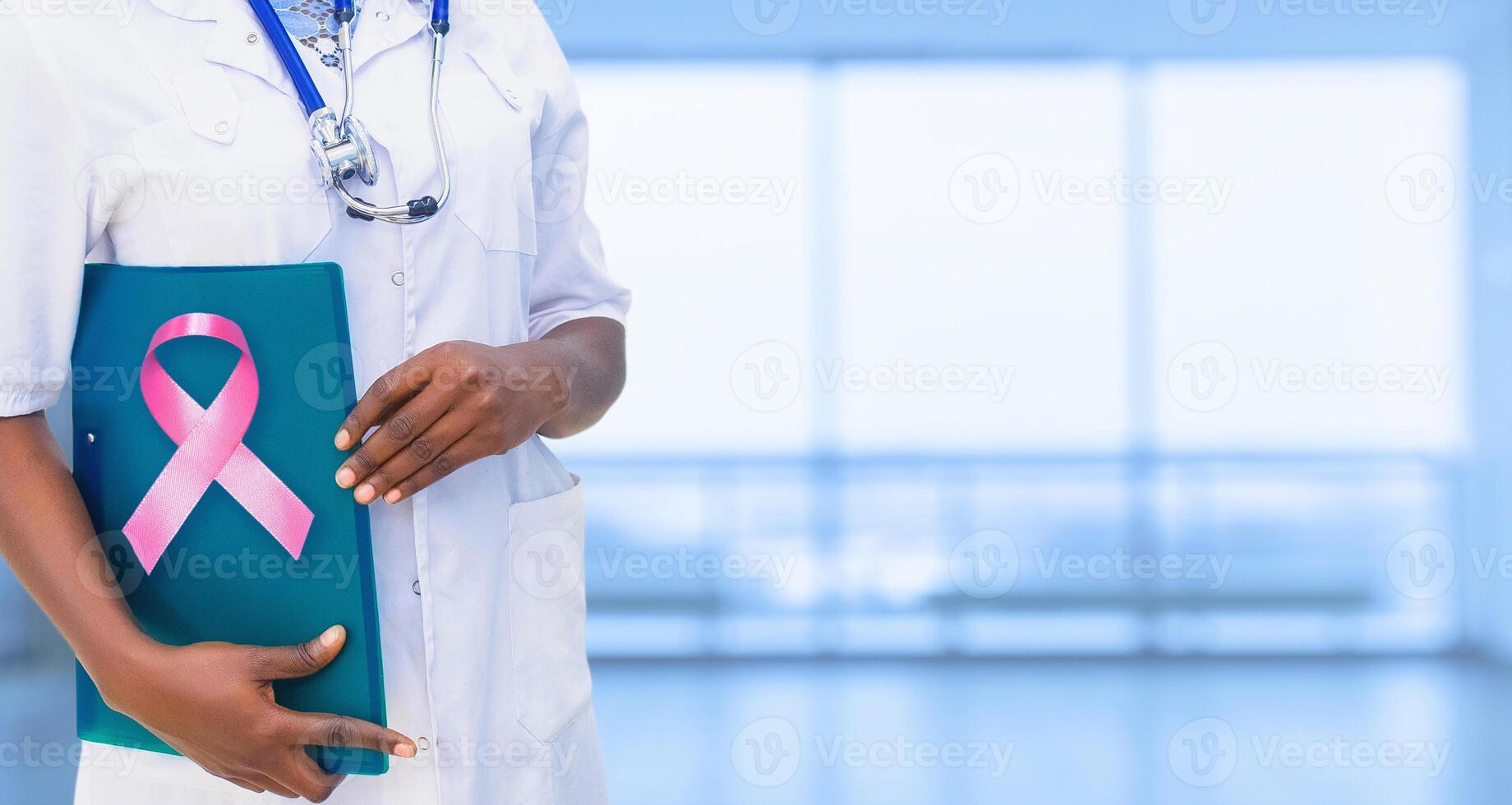 Healthcare, Medicine and Breast Cancer concept. Young beautiful girl of African-American girl in white coat with stethoscope and folder in hospital. An impersonal wide background. photo