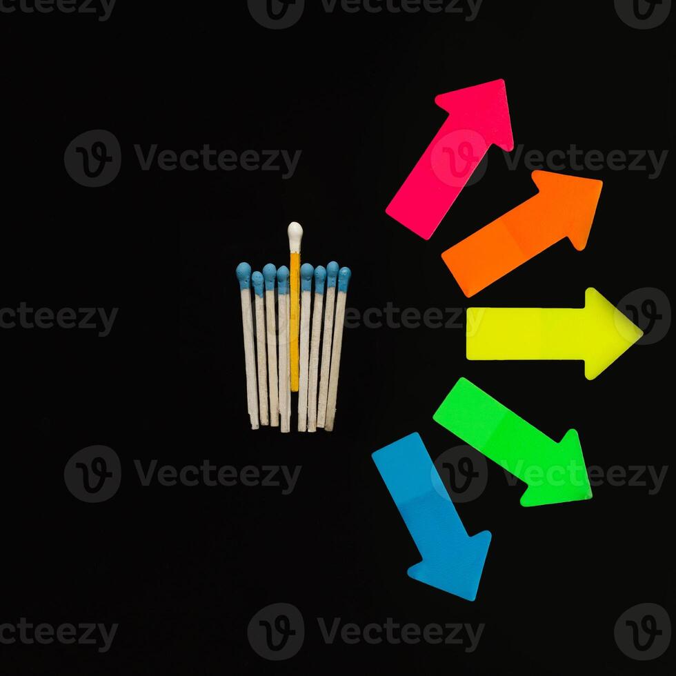 Multi-colored matches on a black background with arrows symbolizing the right to choose. Inclusion. photo