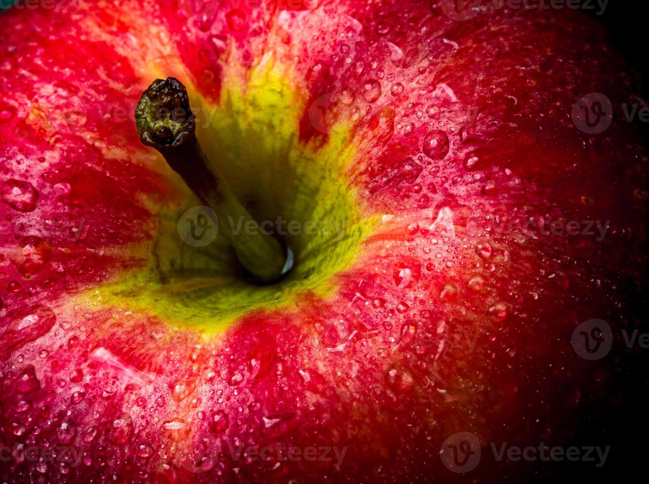 Water droplet on glossy surface of red apple on black background photo
