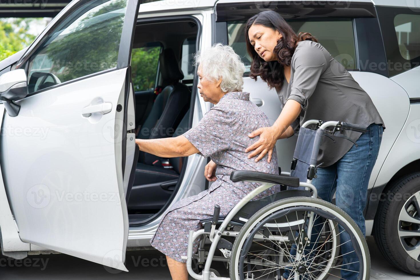 Caregiver help and support asian elderly woman sitting on wheelchair prepare get to her car to travel in holiday. photo