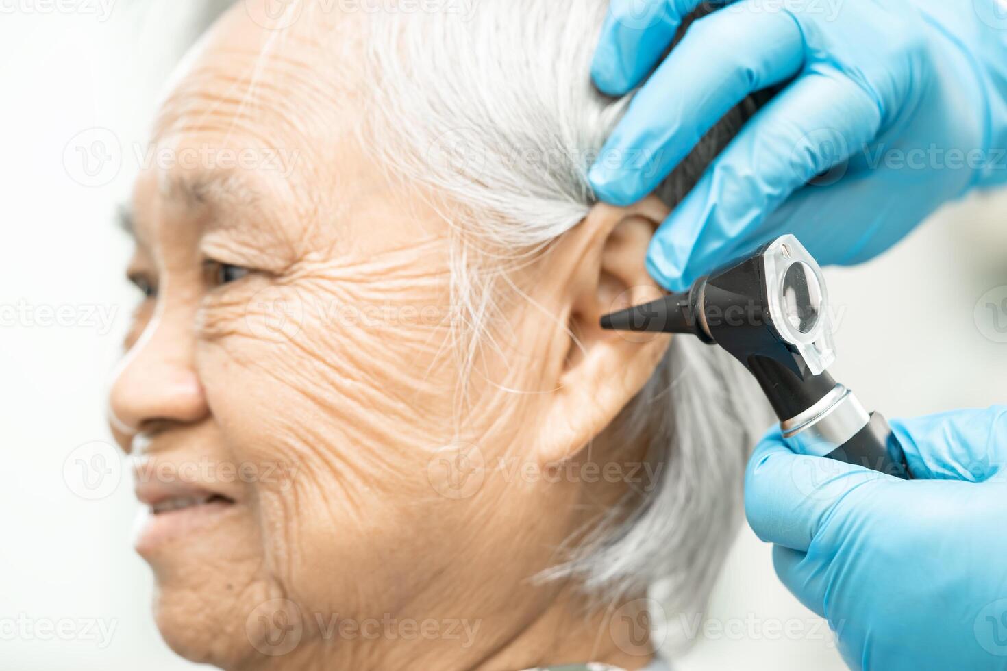 audiólogo o ent médico utilizar otoscopio comprobación oído de asiático mayor mujer paciente tratando escuchando pérdida problema. foto