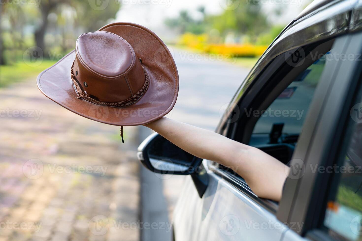 Happy enjoy and freedom in traveling trip with raised hand and holding hat outside of window car in summer vacation holiday. photo