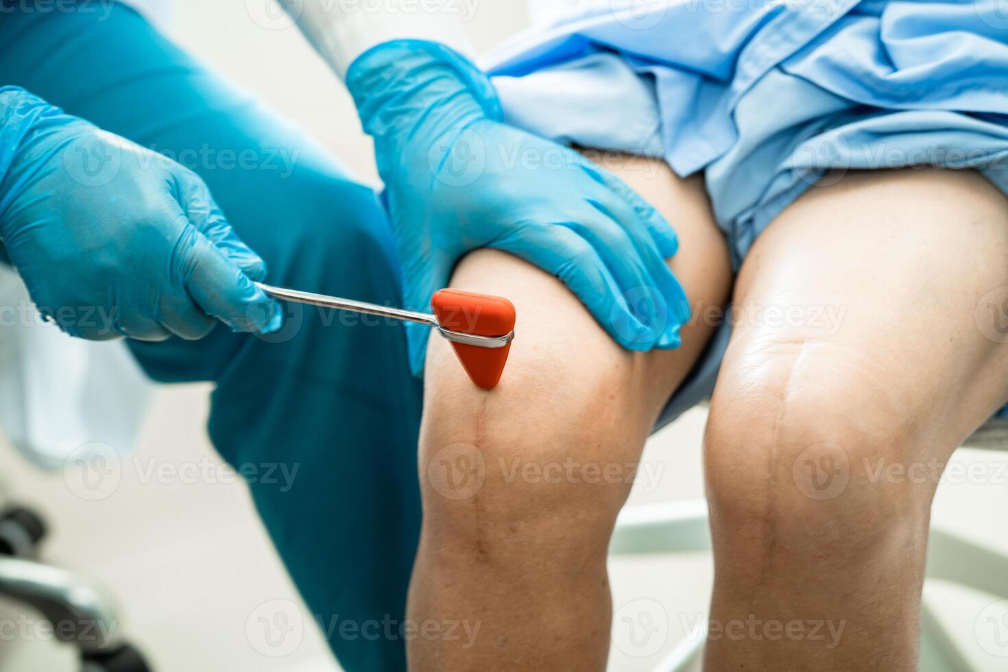 Asian doctor use hammer knock senior woman patient to check knee reflex, nerve and muscle in hospital. photo
