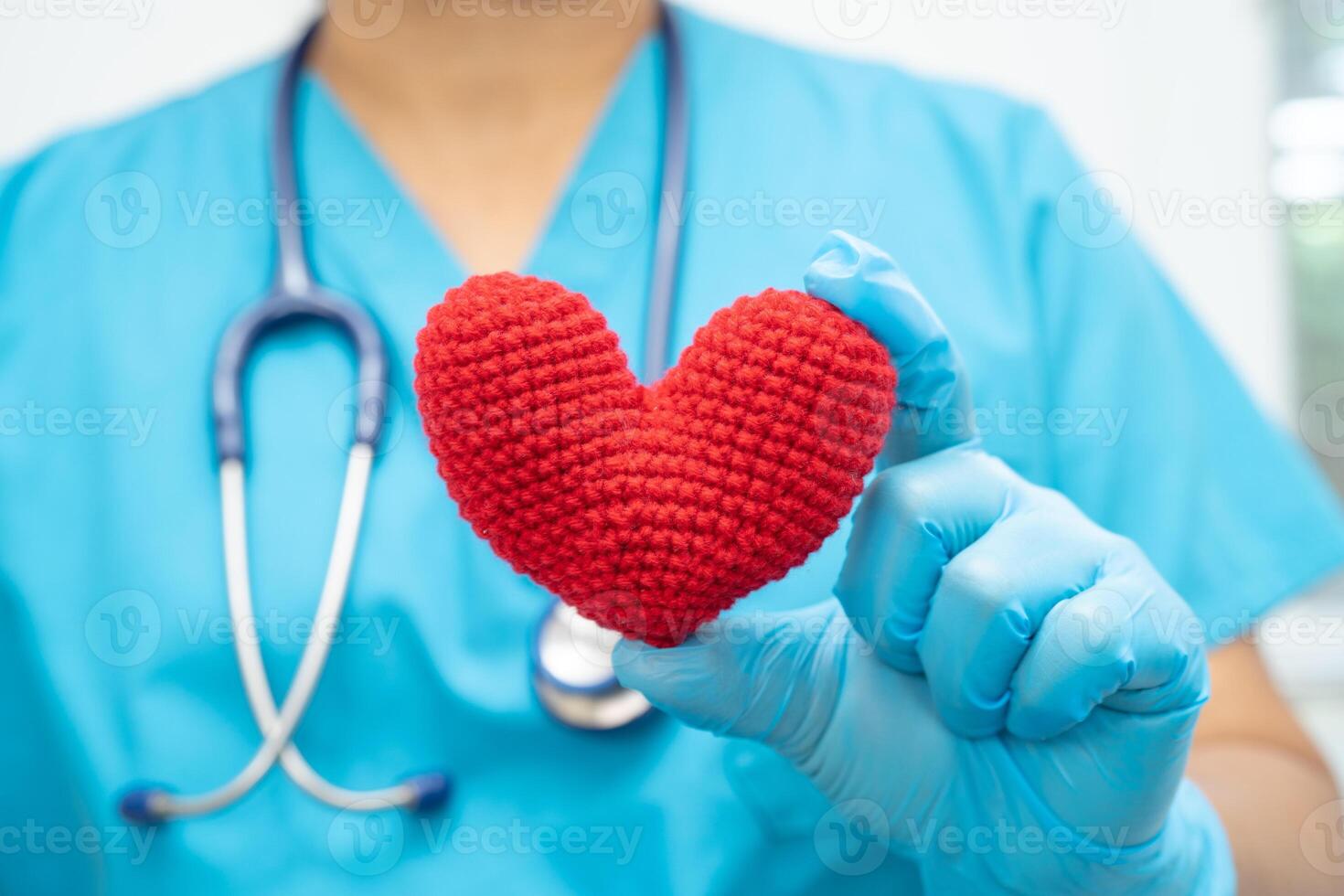 Doctor holding a red heart in hospital ward, healthy strong medical concept. photo