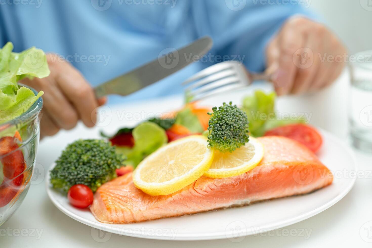 Asian elderly woman patient eating salmon steak breakfast with vegetable healthy food in hospital. photo