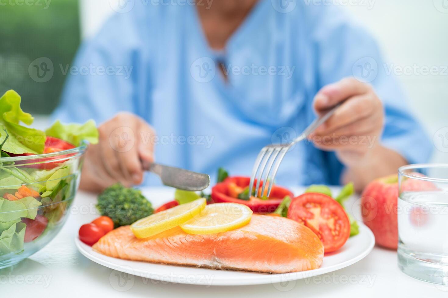 Asian elderly woman patient eating salmon steak breakfast with vegetable healthy food in hospital. photo