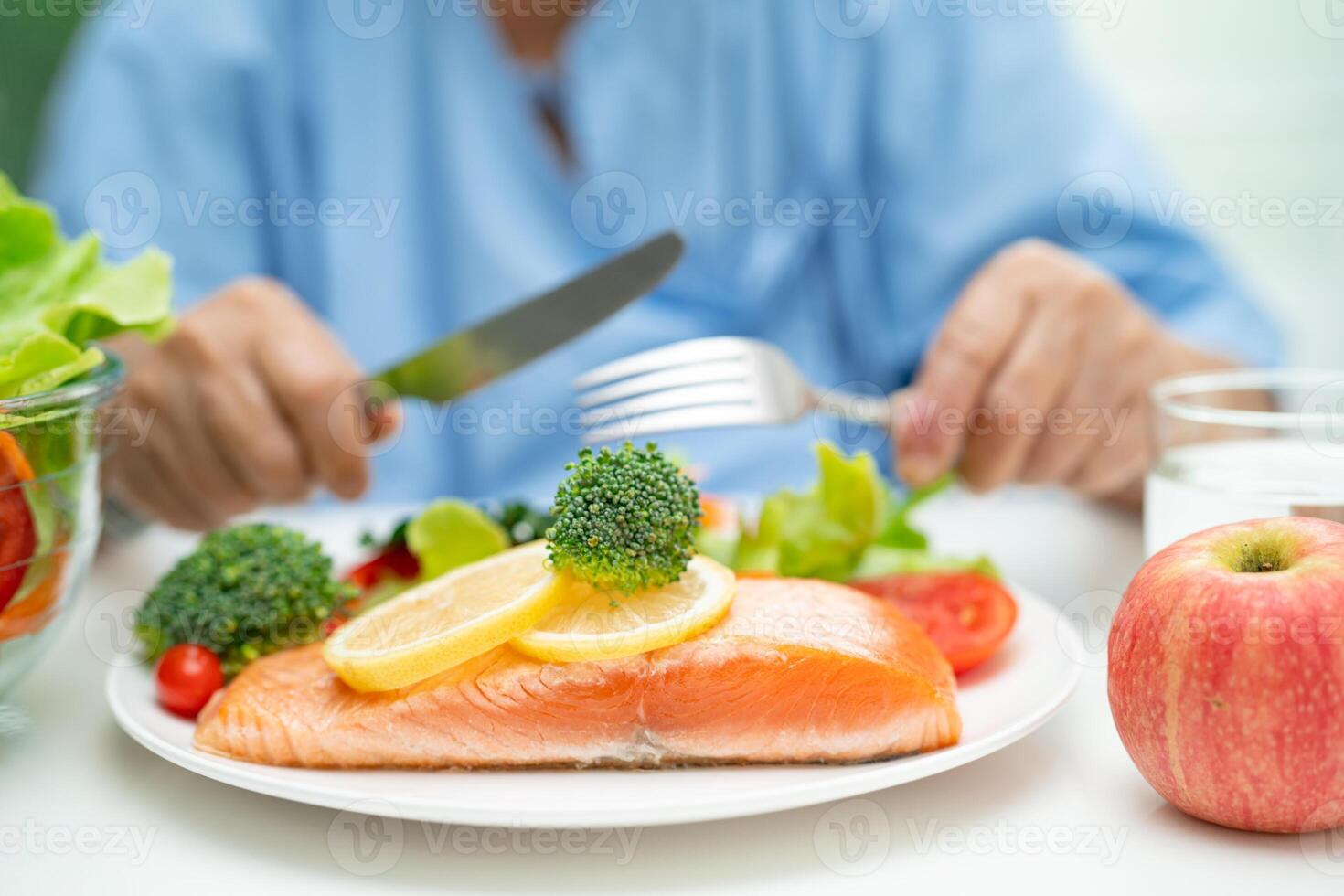 Asian elderly woman patient eating salmon steak breakfast with vegetable healthy food in hospital. photo