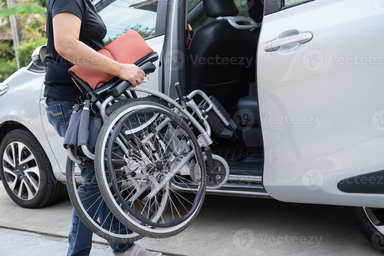 asiático invalidez mujer en silla de ruedas consiguiendo en su auto, accesibilidad concepto. foto
