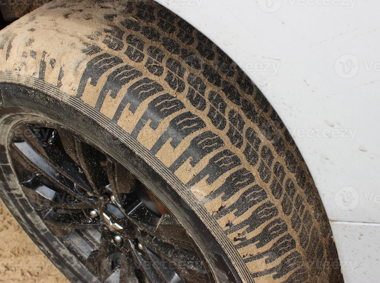 Tread blocks of car tire covered by sand after extreme off road adventure photo