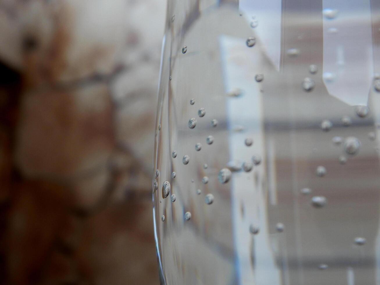 lado de un vaso con ligeramente gaseado mineral agua y un pocos burbujas en borroso fondo foto