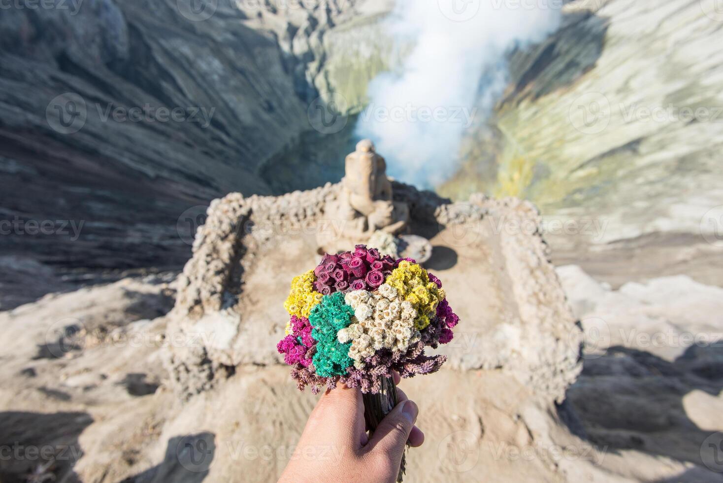 Cropped shot view of someone hand holding flowers for praying and offering to Ganesha statue the Hindu god located on Mt.Bromo crater in East Java of Indonesia. Popular culture of Indonesian people. photo