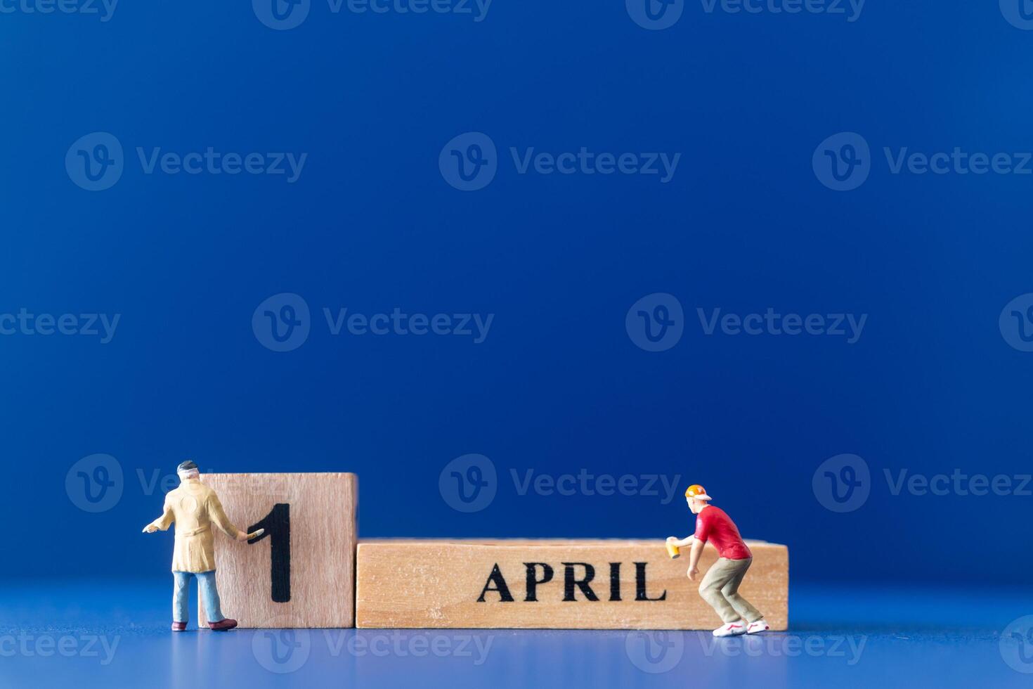 Miniature people painting a wooden block on April 1st photo