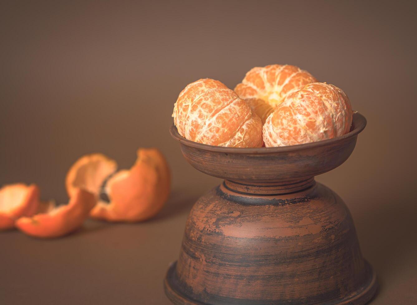 Three Tangerines in a clay plate and peel on the table. Vitamin-C photo