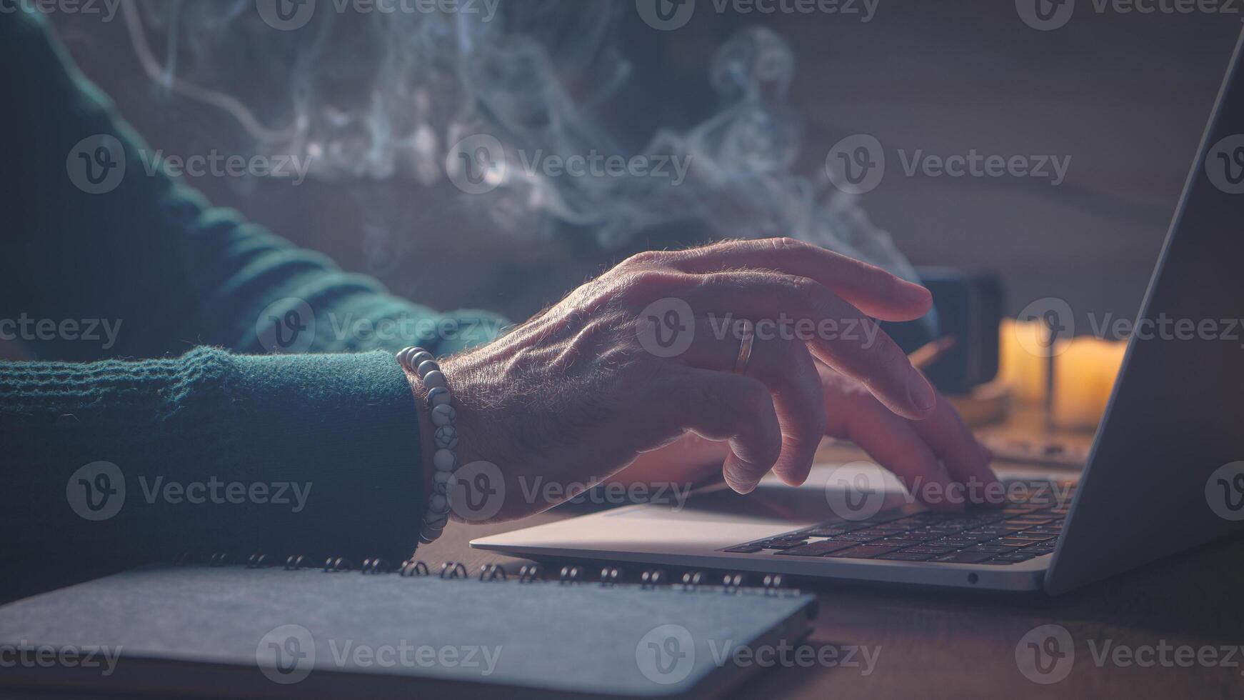 Home Office. Man, Laptop, notepad, music speaker incense. A man in a green sweater. photo