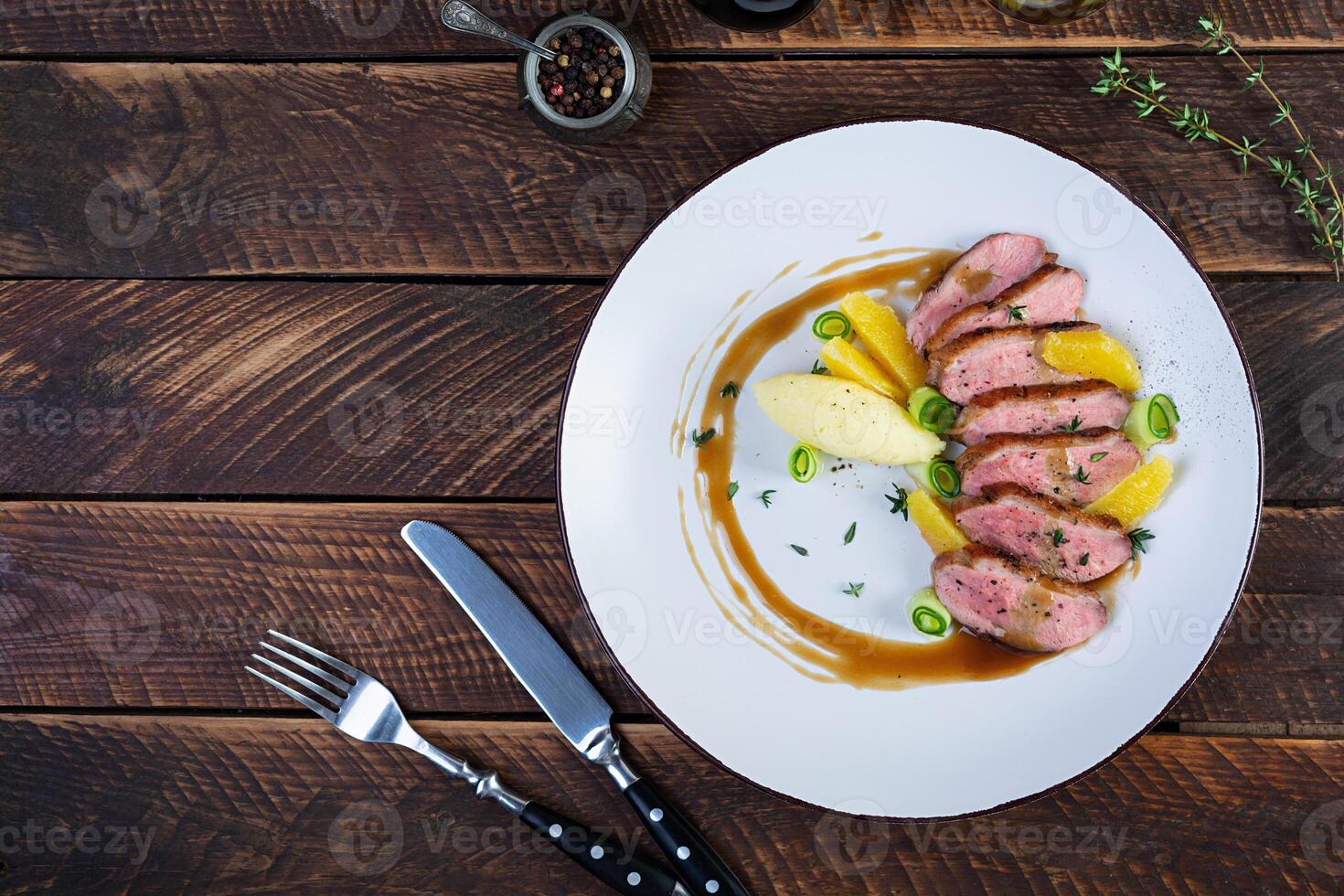 Roast duck fillet with mashed potato and orange sauce on wooden background photo