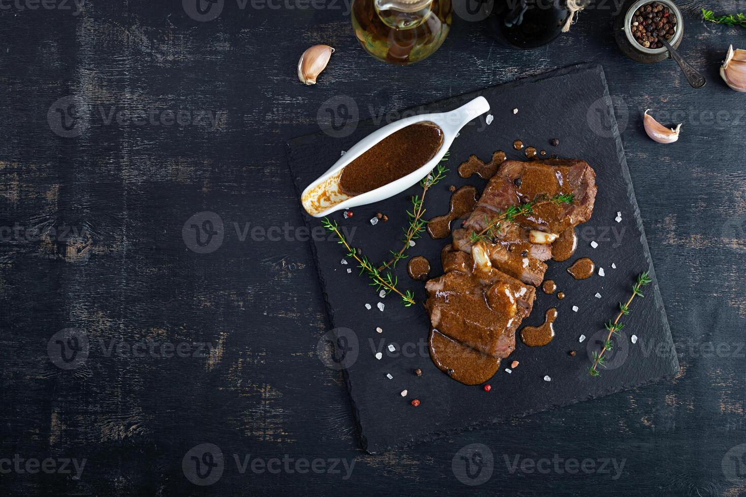 Grilled beef steak with herbs and spices on stone plate photo