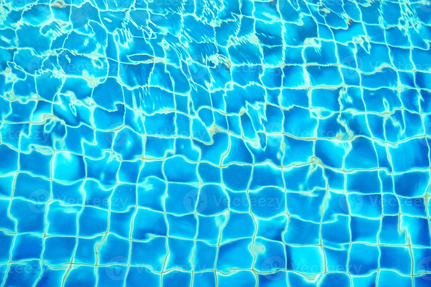 blue water wave pattern in swimming pool as the sun shines down during the day. Soft and selective focus. photo