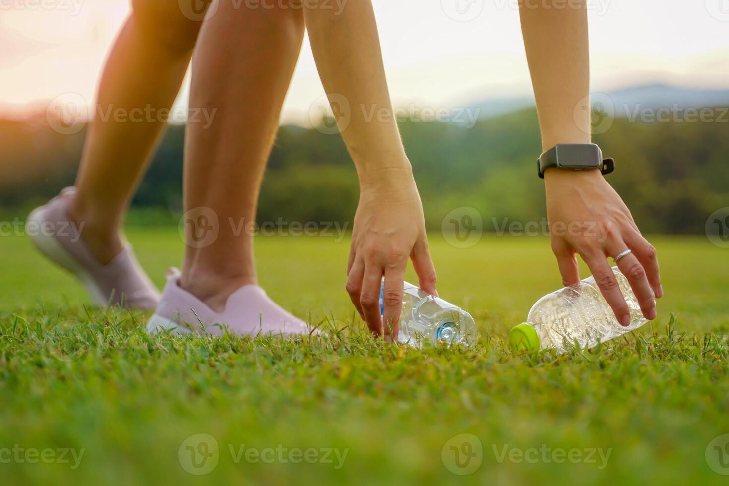 People help pick up trash from plastic bottles left on the lawn. Soft and selective focus. photo