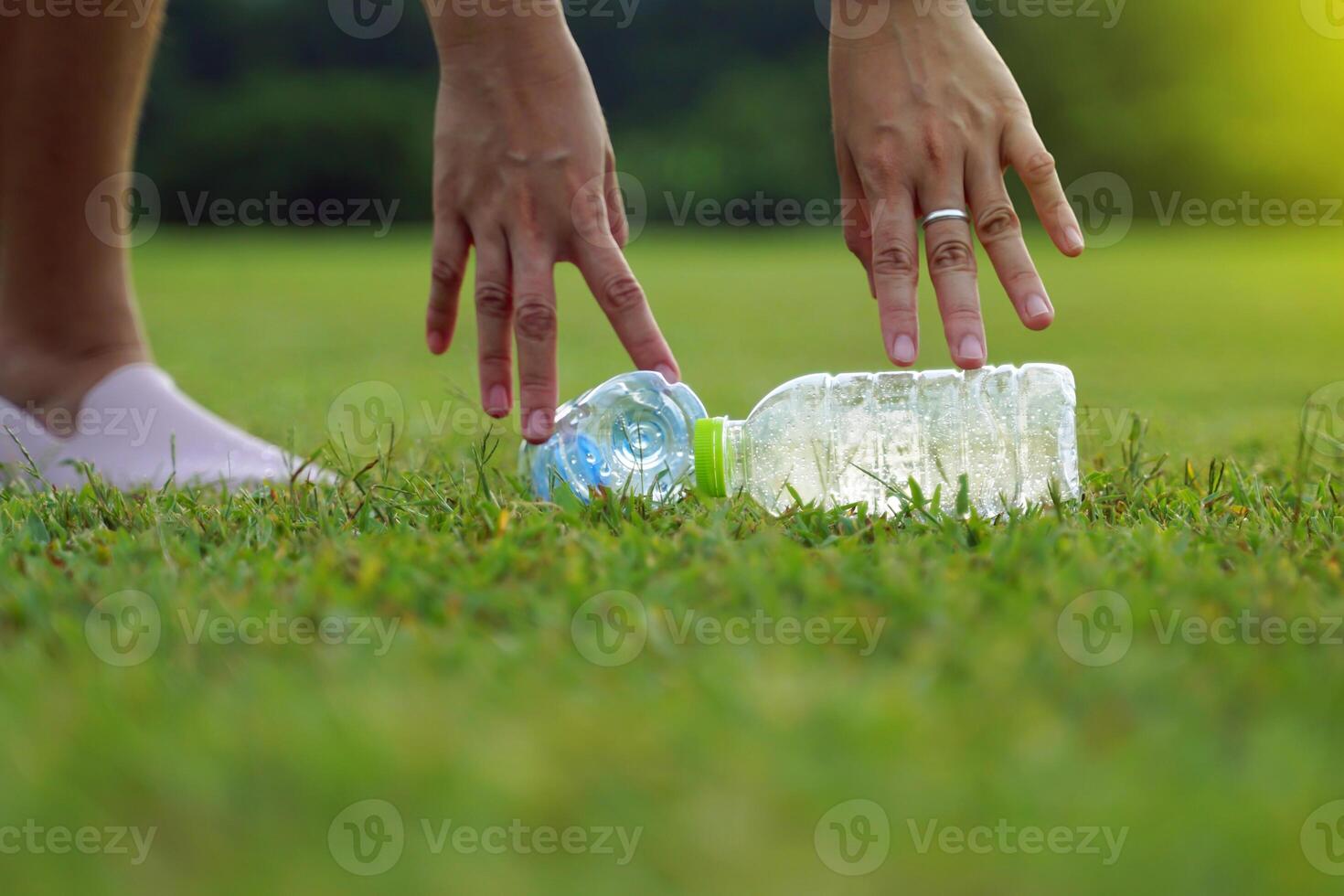 People help pick up trash from plastic bottles left on the lawn. Soft and selective focus. photo