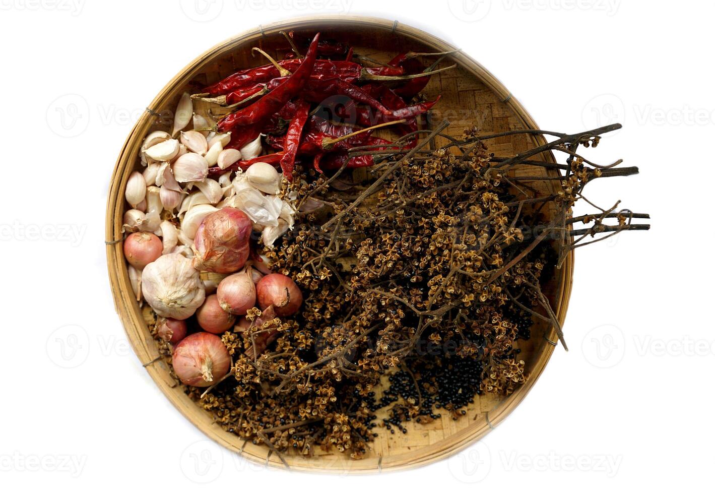 isolated dried chilies, Zanthoxylum, garlic cloves and shallots on a bamboo basket on a white background. It is an ingredient in Thai curry paste. photo