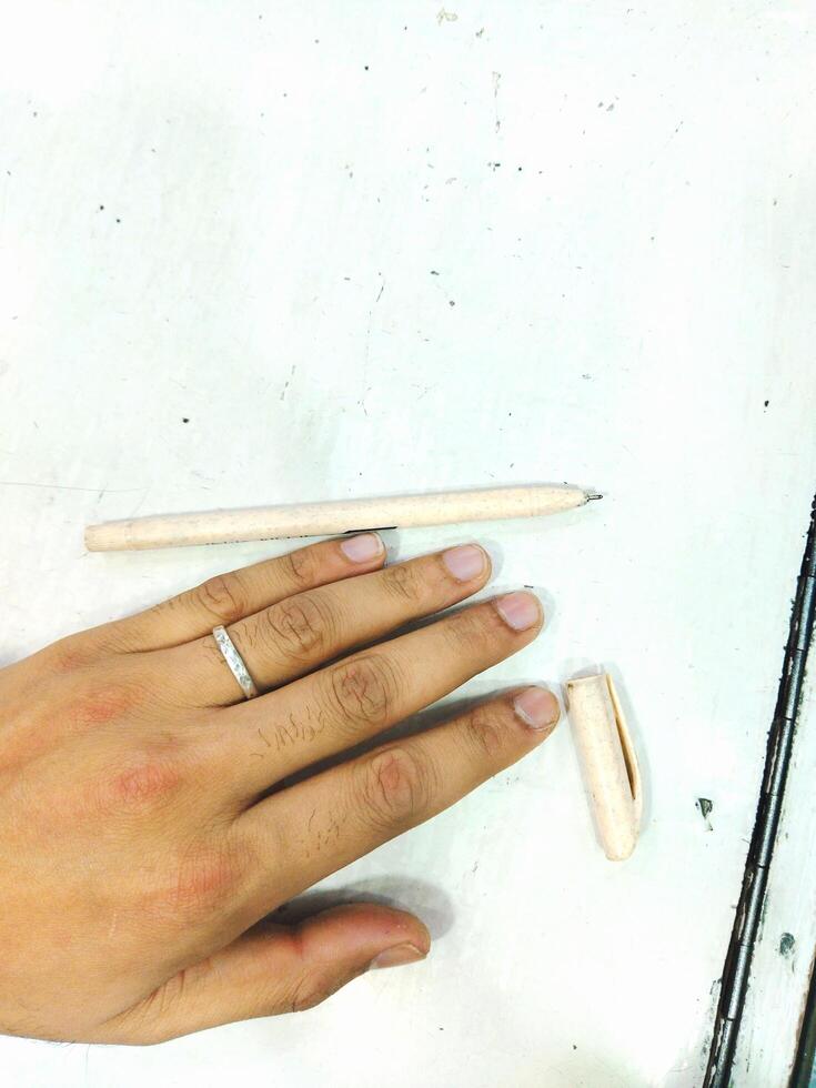 a person's hand holding a pencil and a wooden pen photo