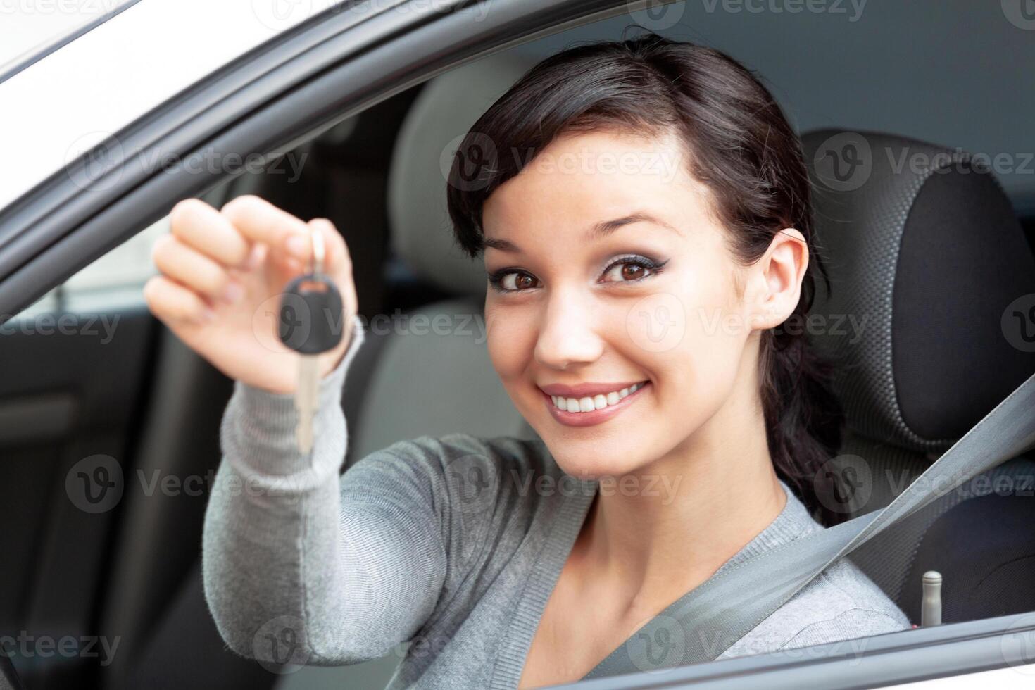 Happy owner of a new car is showing the car key. Pretty girl driver photo