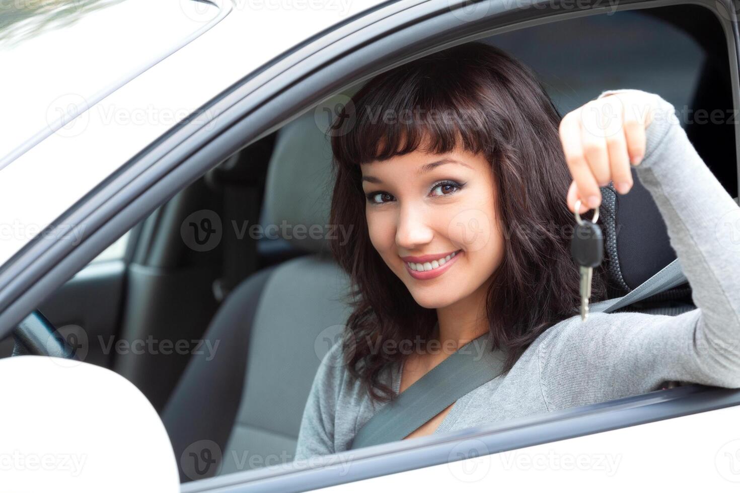 joven contento mujer conductor sostener coche llaves en su nuevo coche foto