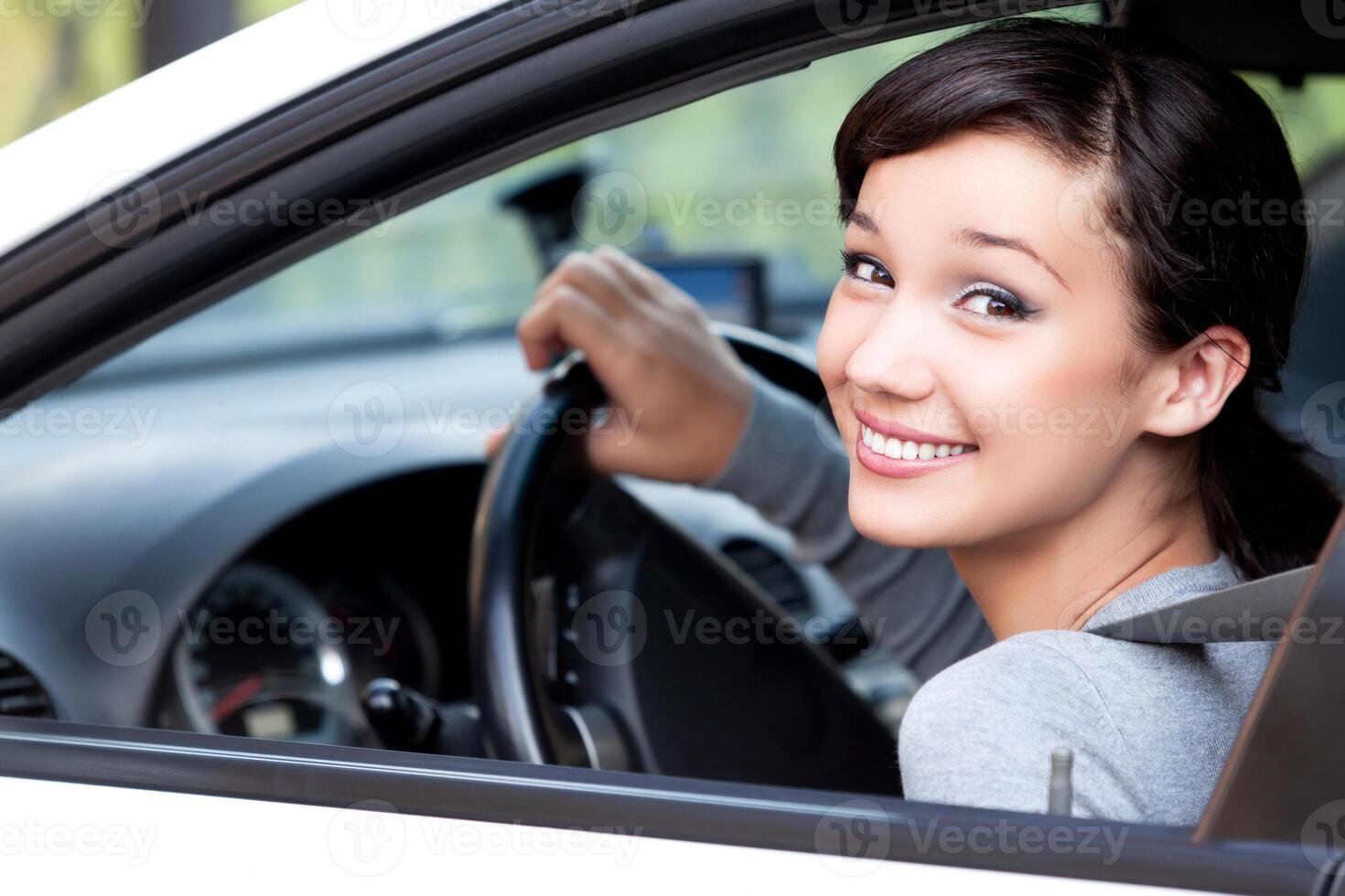 contento propietario de un nuevo coche. bonito mujer conductor sonriente a usted desde su automóvil foto