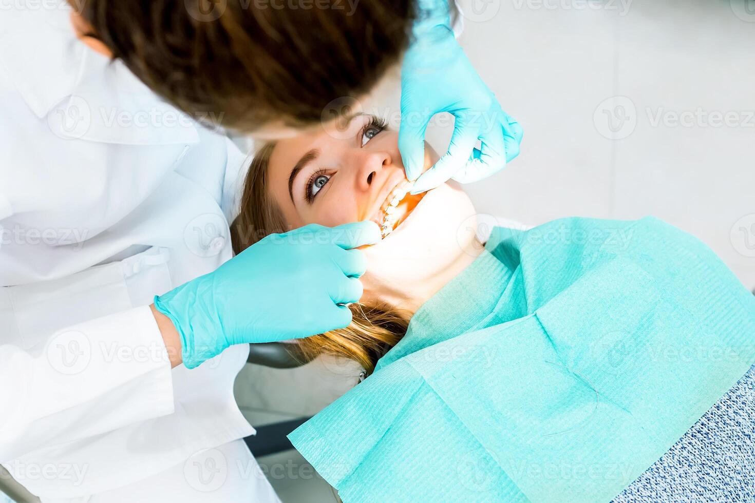 Female dentist checking up patient teeth with braces at dental clinic office. Medicine, dentistry concept. Dental equipment. Close up. photo