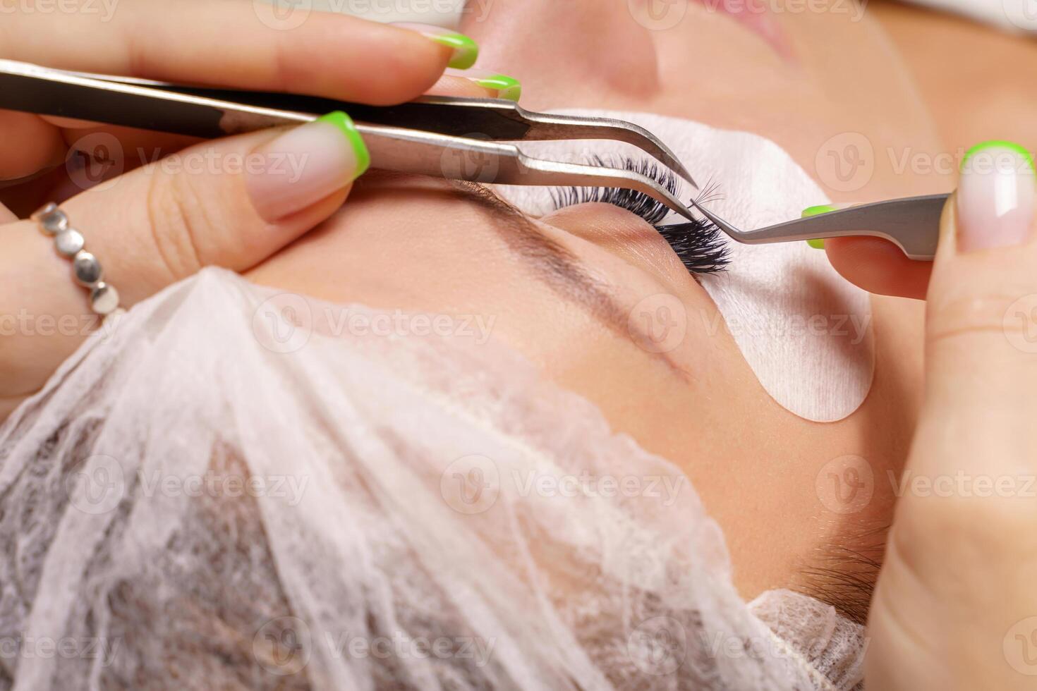 Eyelash Extension Procedure. Woman Eye with Long Eyelashes. Close up, selective focus. photo