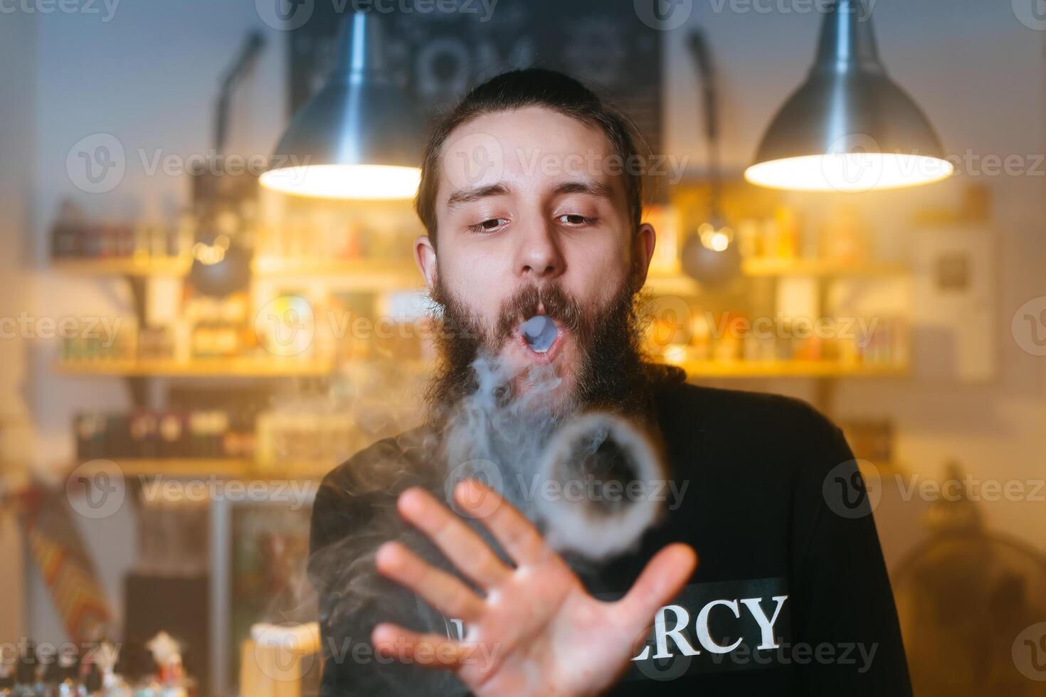 Young Men with beard vaping and releases a cloud of vapor. close-up. photo