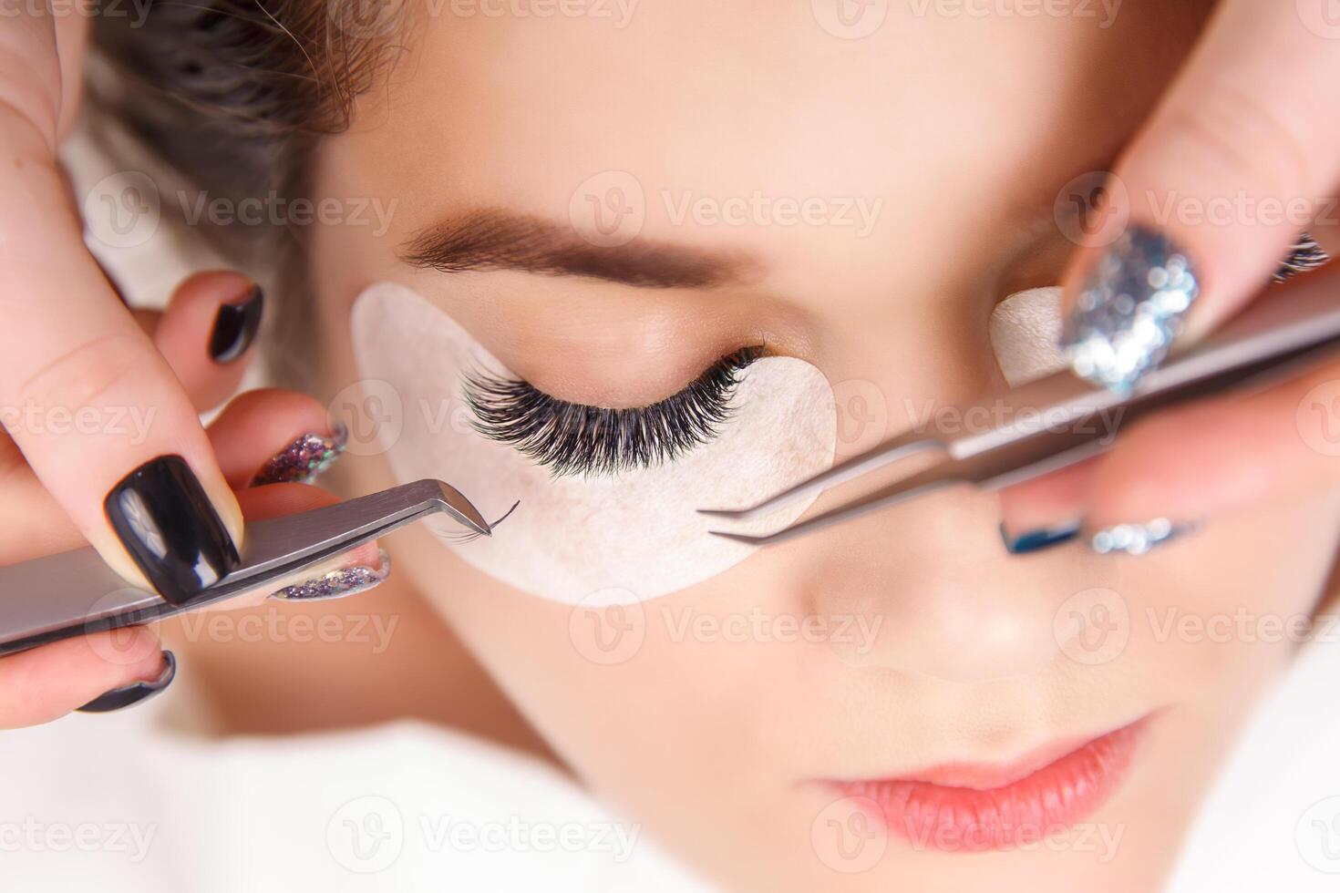 Eyelash Extension Procedure. Woman Eye with Long Eyelashes. Close up, selective focus. photo