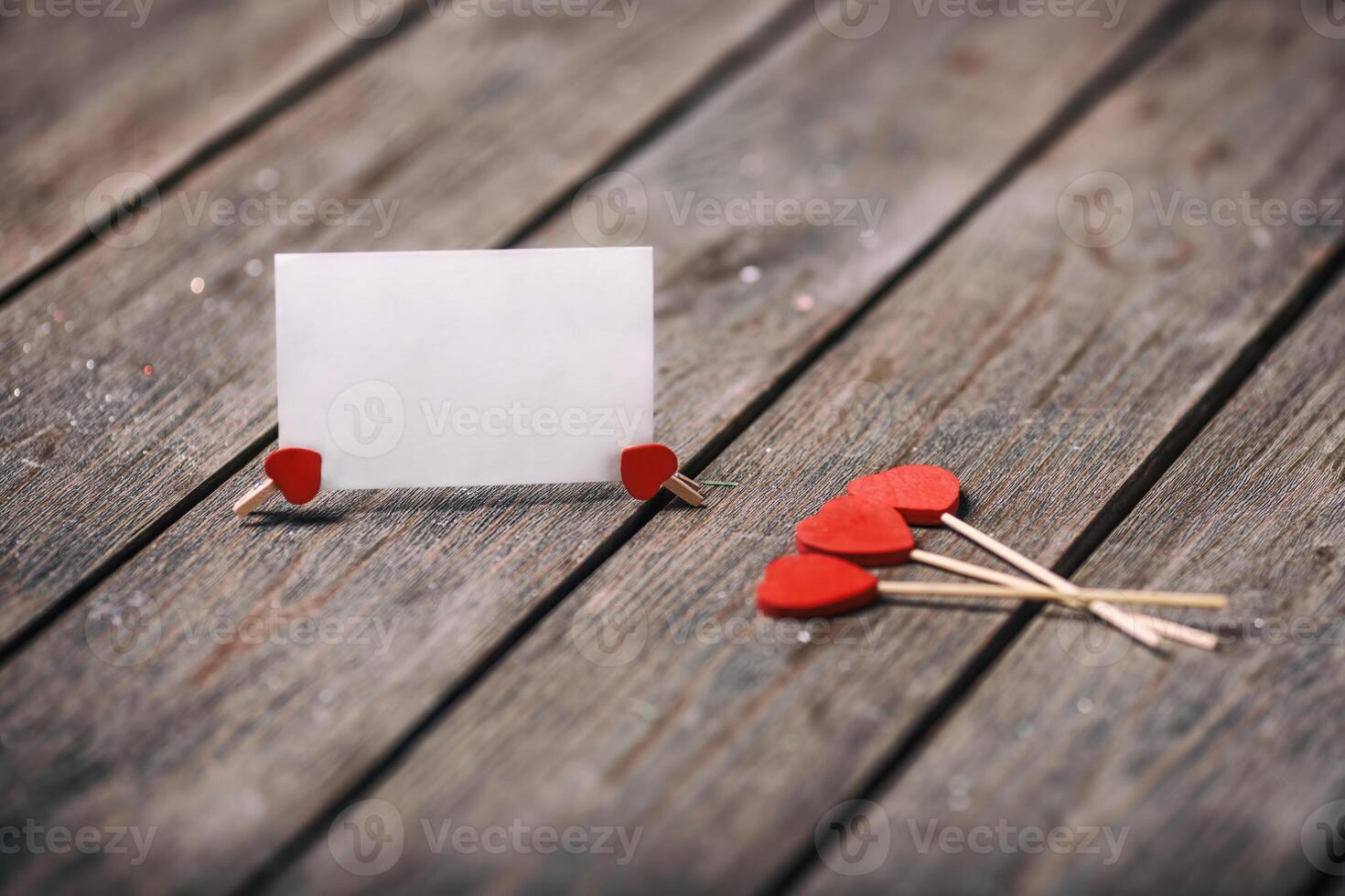 Three red hearts shape on stick with paper card over wooden background. Valentine concept. selective focus. Copyspace for text. photo