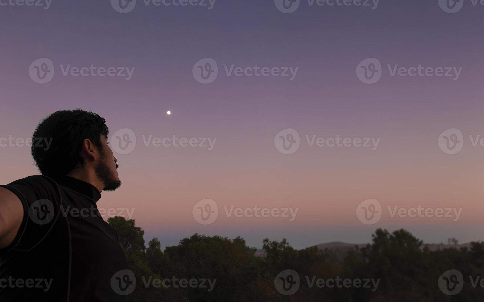 Thoughtful man looking at the sky with beautiful sunset in the background and space for text photo