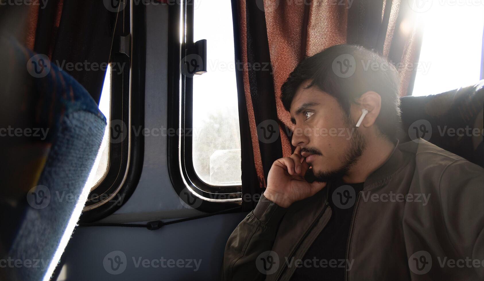 Thoughtful young man traveling and sitting in an economy bus, with space for text photo