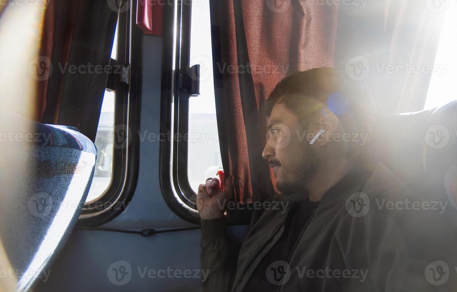 Smiling young man traveling and sitting in economical bus, with space for text photo