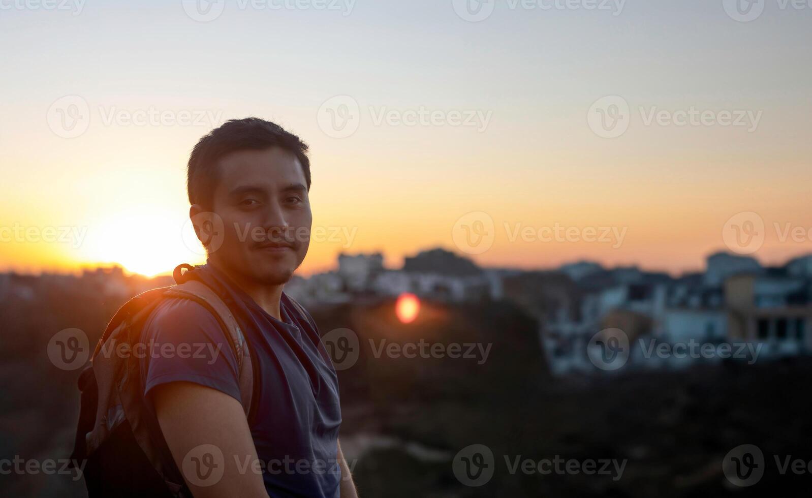 Smiling travel man with backpack at sunset and space for text photo