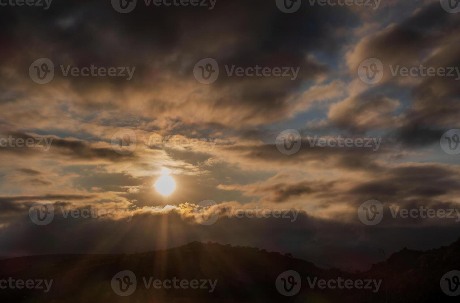 Sunset with sun rays between the clouds, mystical scene with space for text photo