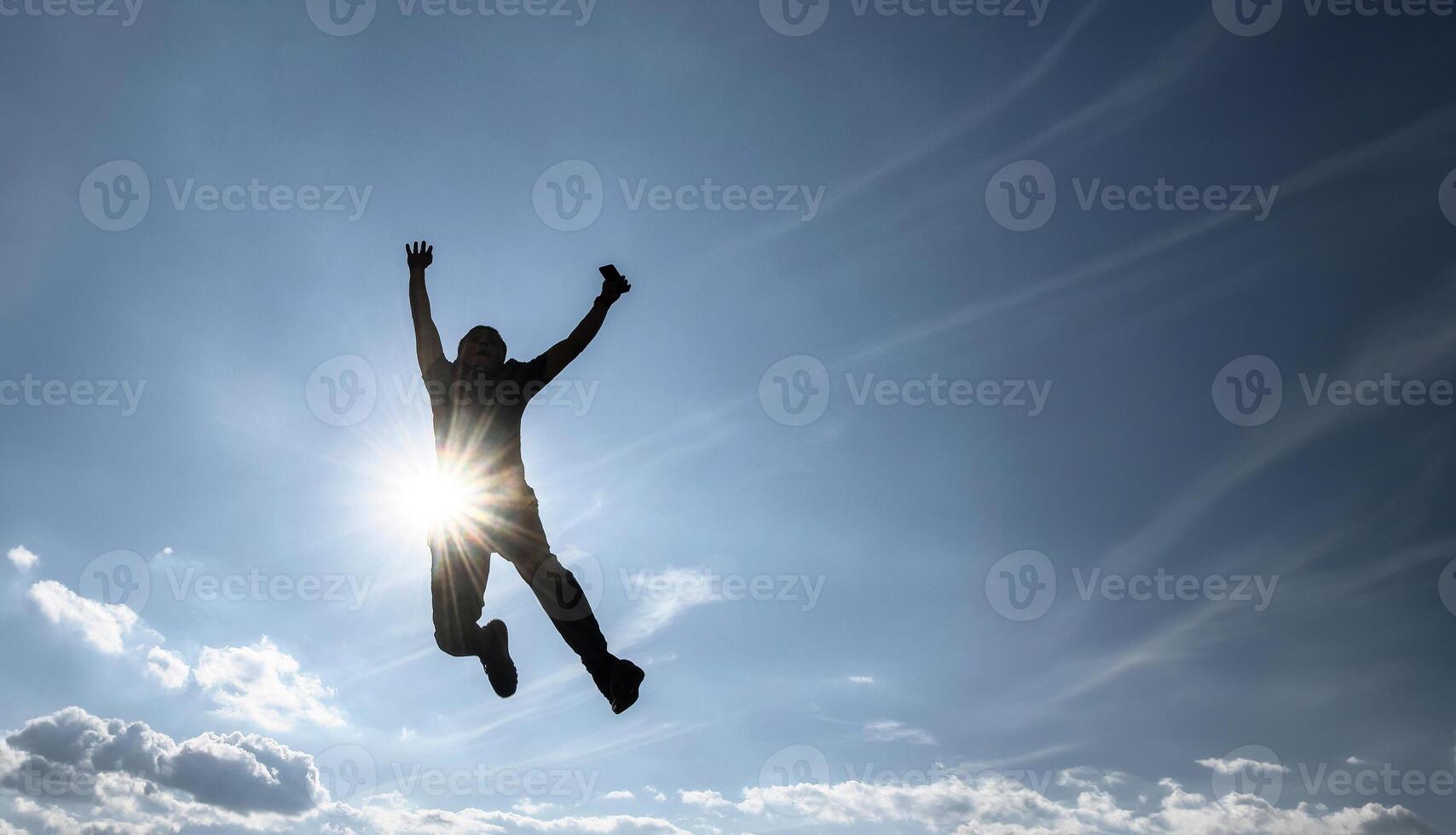 Man jumping with full sky background, sun rays, enjoying a moment of success, with space for text photo