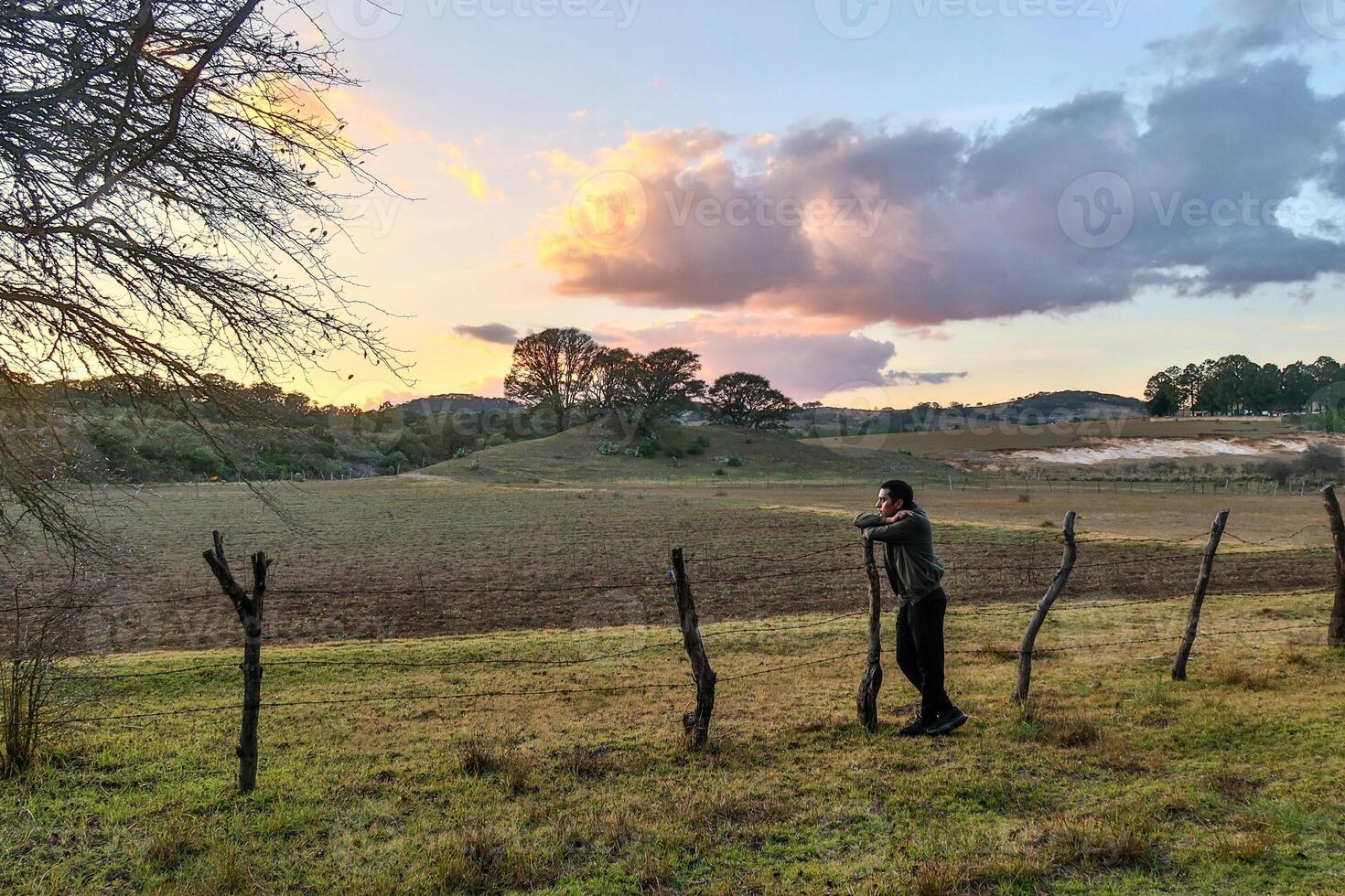 Young man thoughtful and reflecting, looking at the sunset with beautiful clouds and space for text photo