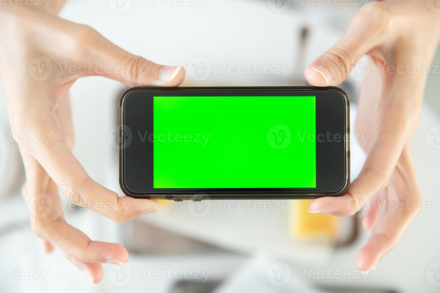 closeup hand holding smartphone top view in restaurant with blank space green screen colored photo