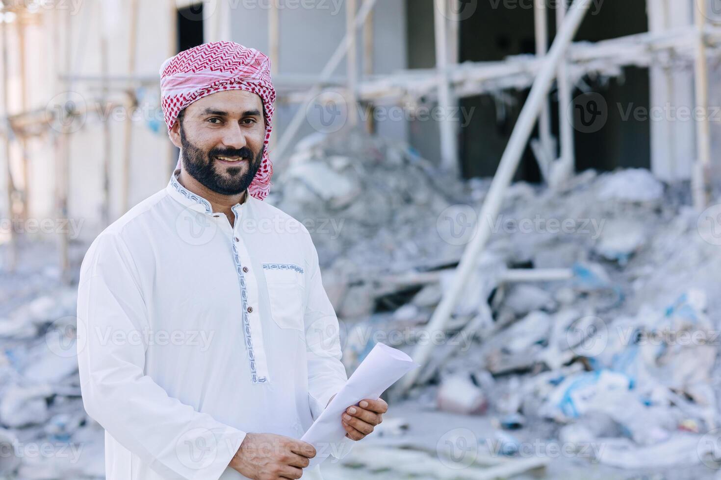 árabe musulmán adulto ingeniero negocio masculino retrato en pie con piso plan a construcción sitio foto
