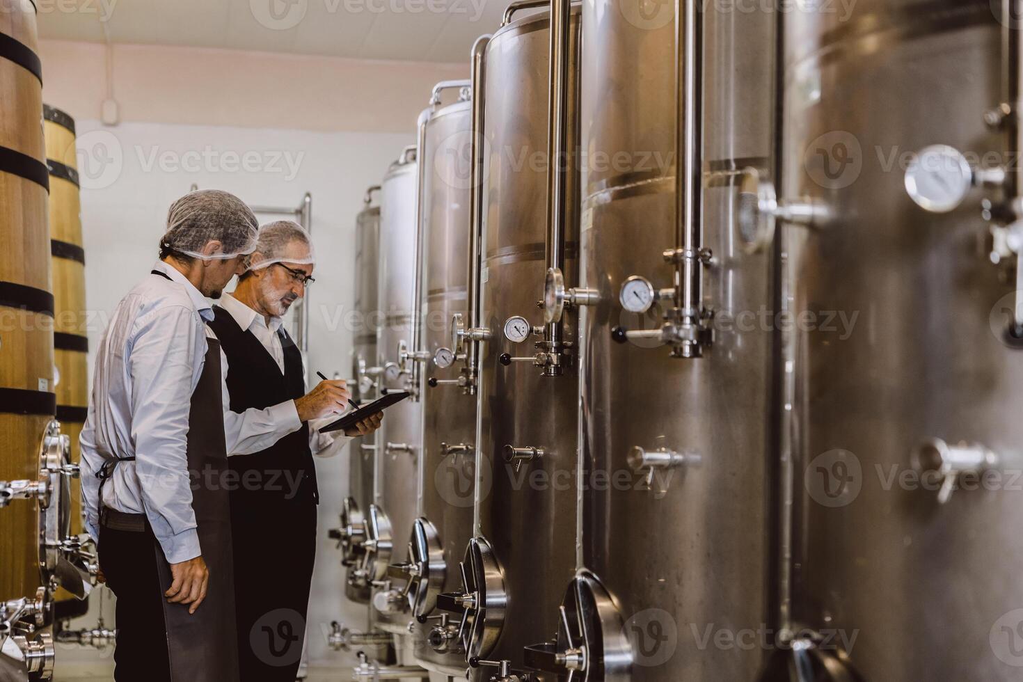 Winemaker professional working in modern large winery factory liquor alcohol drinks industry quality control and fermentation monitor vintage color tone photo