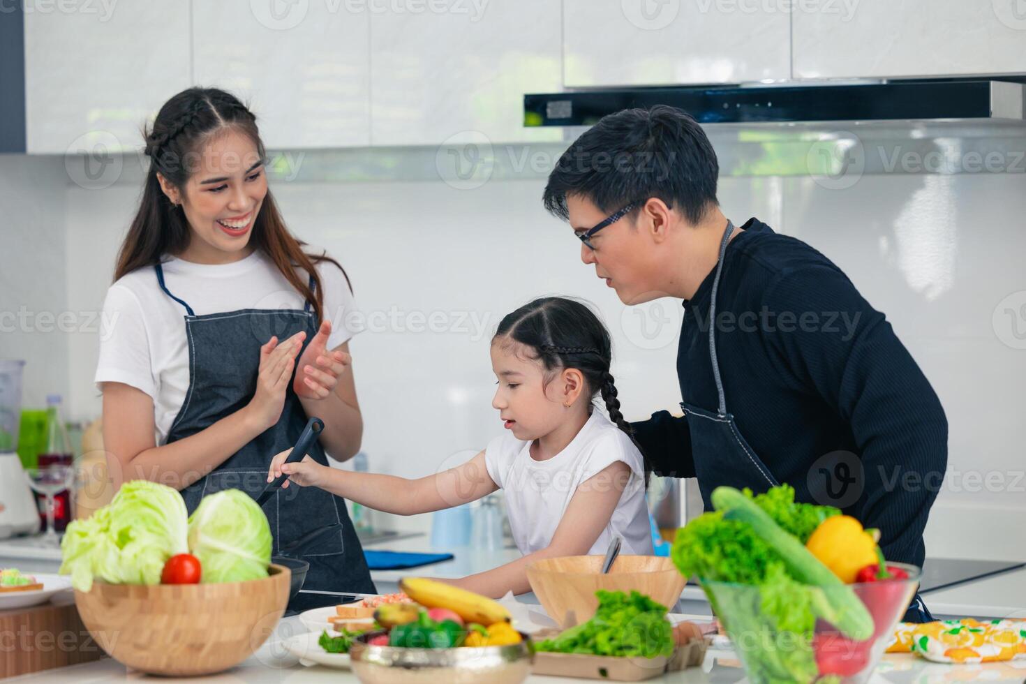 Child playing cook food with father and mother at home kitchen. Asian family happiness moment together. photo