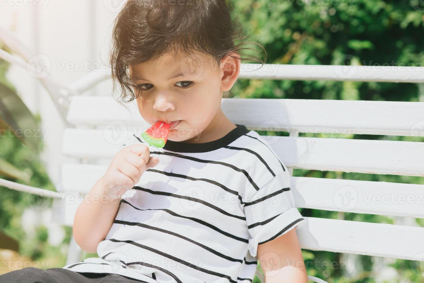 cute latin indian kid child eating sweet fruit ice cream sitting outdoor colorful lovely. photo